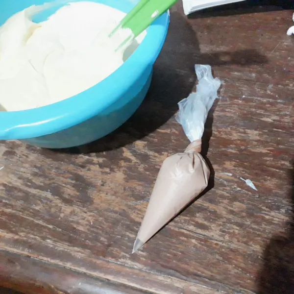 Ambil 3 sdm adonan. Tambahkan pewarna coklat. Aduk rata, masukkan dalam plastik segitiga.
