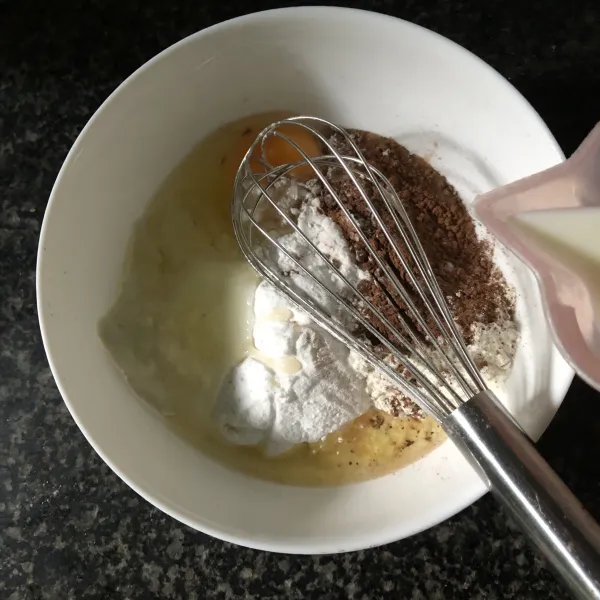Tuang susu perlahan sambil diaduk. Lalu aduk pakai whisk dengan rata.