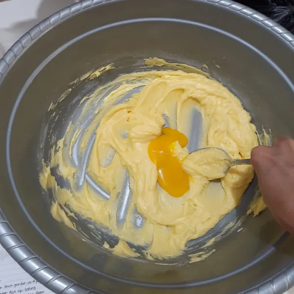 Setelah rata, masukkan kuning telur satu persatu sambil diaduk rata.