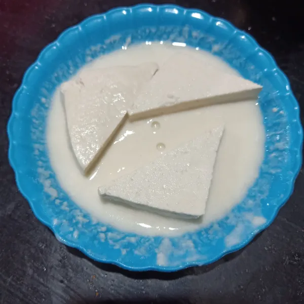 Ambil 3 sdm tepung bumbu lalu larutkan dengan sedikit air es, lalu baluri tahu sampai rata.