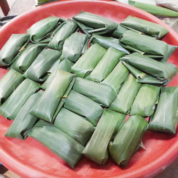 Ambil sedikit adonan letakkan di atas daun pisang, tambahkan daun pandan, gulung daun pisang & lipai ujung-ujungnya.