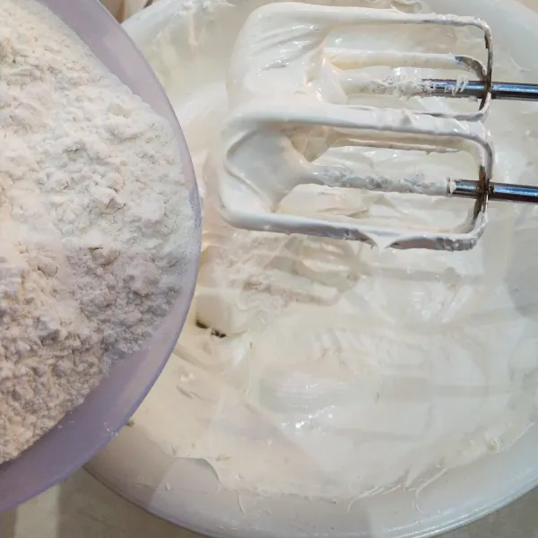 Setelah adonan putih kental dan berjejak masukkan dikit demi sedikit tepung terigu dan santan aduk dengan mixer atau spatula dengan kekuatan rendah