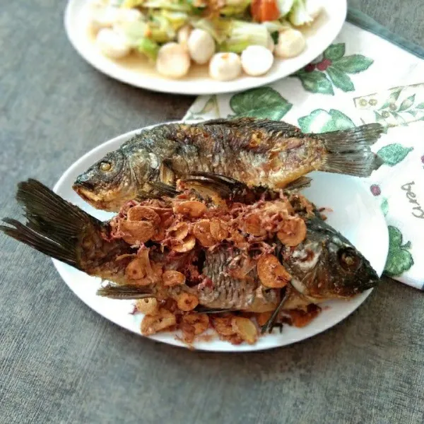 salin ikan mas goreng dalam piring, taburi dengan kecombrang dan bawang putih goreng, sajikan.