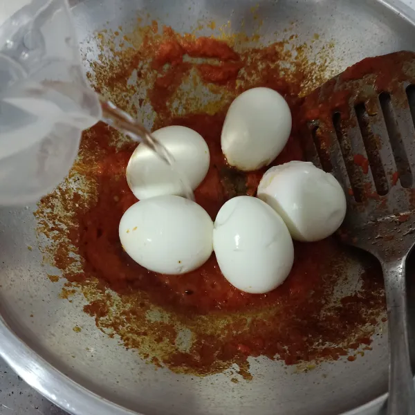 Masukan telur rebus lalu tambahkan air dan air asam, aduk rata.