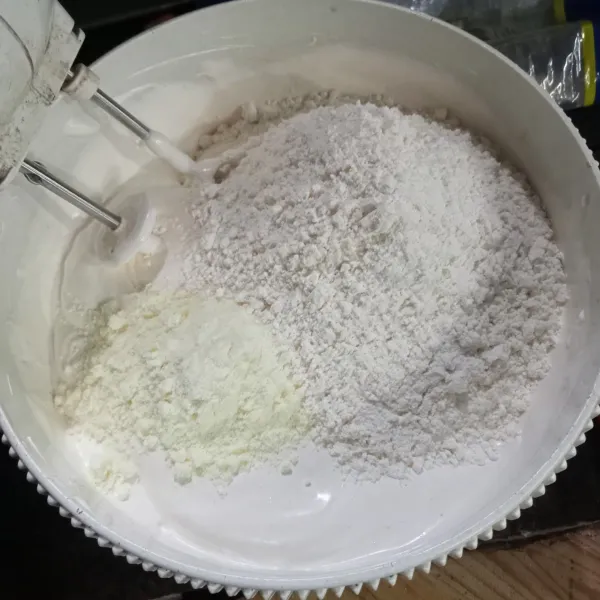 Masukkan tepung terigu dan susu bubuk, kocok dengan speed rendah asal tercampur saja.