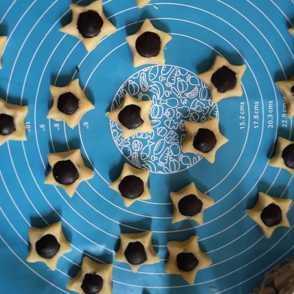 Timbang adonan sebesar 10 gram kemudian bulatkan lalu tempelkan coklat koin dan cubit ujungnya sehingga membentuk bintang.