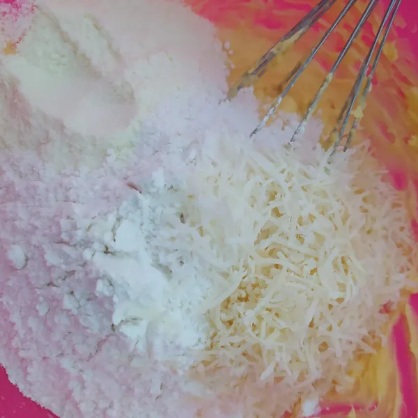 Kemudian tambahkan tepung terigu, susu bubuk dan keju parut. Aduk rata hingga membentuk adonan.