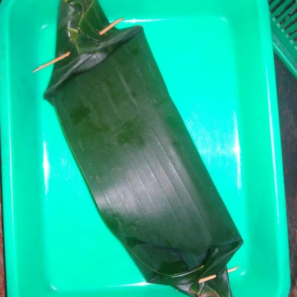 Siapkan daun pisang, masukkan ikan beserta bumbu nya, gulung lalu sematkan ujungnya dengan lidi.