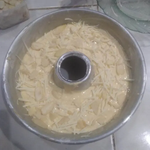 Masukkan ke dalam loyang yang sudah dioles margarin. Beri toping keju parut dan almond slices. Hentakkan pelan sebanyak 3x.