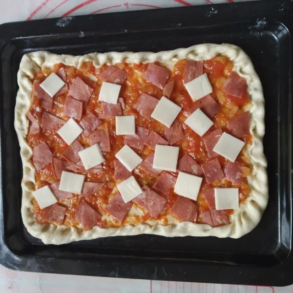 Pindahkan dalam loyang, olesi dengan saus tomat kemudian beri topping sesuai selera, lipat pinggiran pizza