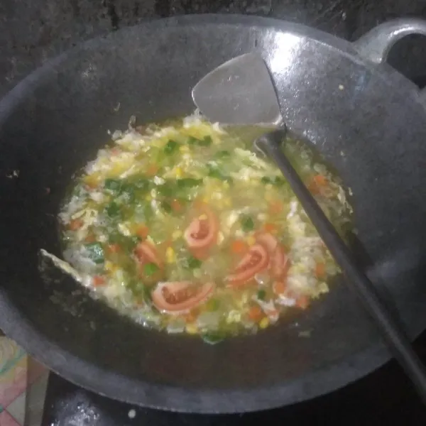 Masukkan tomat, daun bawang dan jagung. Bumbui dengan garam, lada dan kaldu bubuk. Aduk rata.