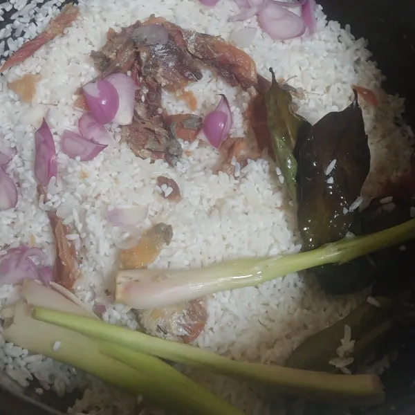 Cuci bersih beras, tambahkan suwiran ikan peda, bawang merah iris, serai, daun salam dan minyak goreng