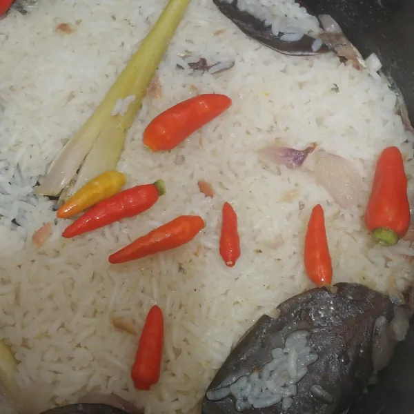 Setelah 1/2 mateng buka rice cooker dan tambahkan cabe rawit utuh tutup lagi sampai nasi matang.