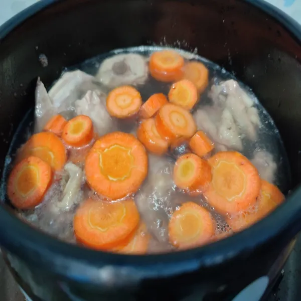 Setelah ayam setengah empuk masukkan wortel, rebus selama 3 menit. Jika masih ada busa dari kaldu, ambil dan buang busanya.