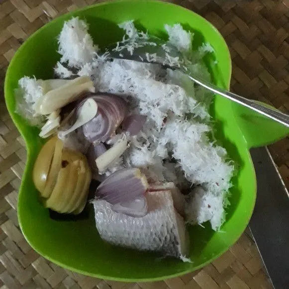 Masukkan kelapa parut, bawang merah, bawang putih, dan tomat, pada mangkuk yang berisi ikan, lalu aduk hingga rata.