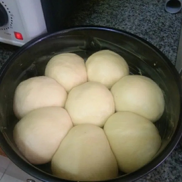 Tata adonan roti di dalam loyang yang sudah diolesi margarin, biarkan kembali mengembang.