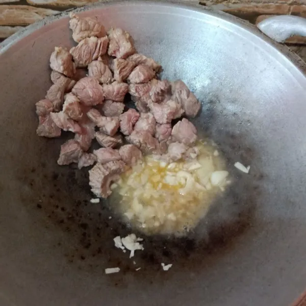 Setelah daging setengah matang, masukkan bawang putih dan 1/2 bawang bombay. Tumis hingga harum.