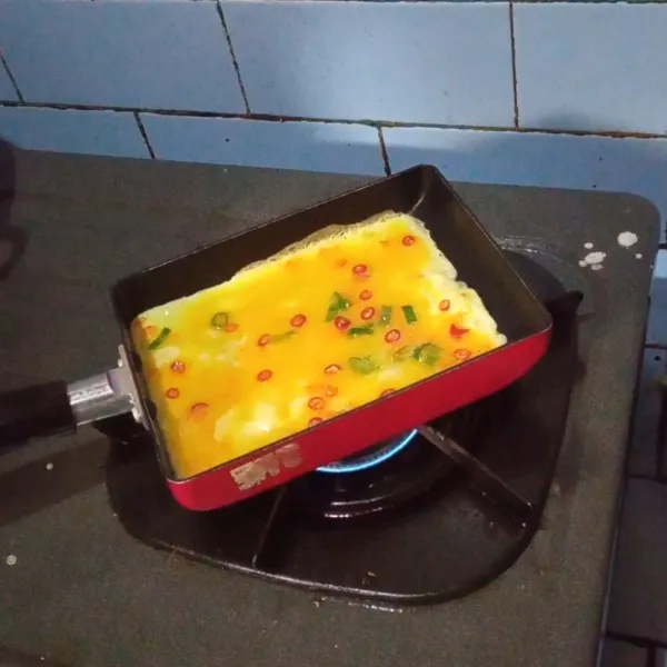 Tuang telur di teflon.