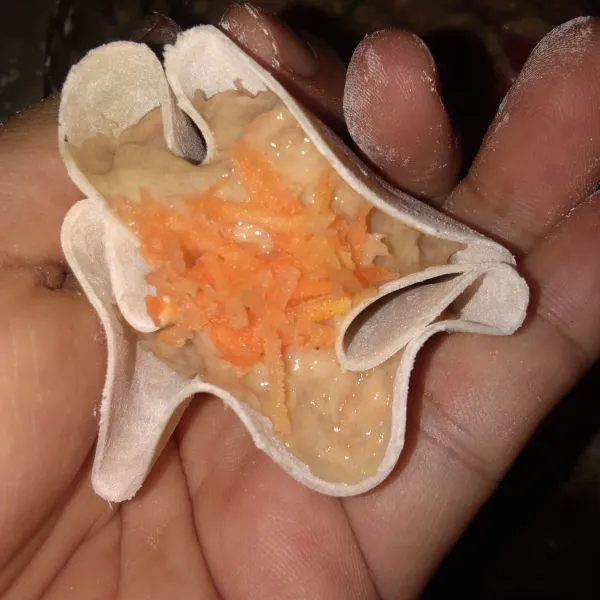 Ambil selembar kulit pangsit lalu beri sesendok isian ayam lalu lipat seperti gambar disamping, taburi dengan sedikit wortel parut.