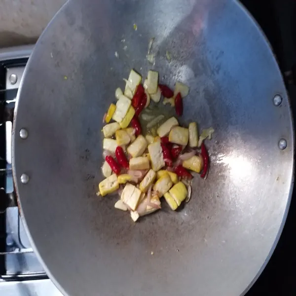 Tumis bawang merah, bawang putih dan tahu. Setelah agak matang, masukkan cabai untuk ditumis hingga matang.
