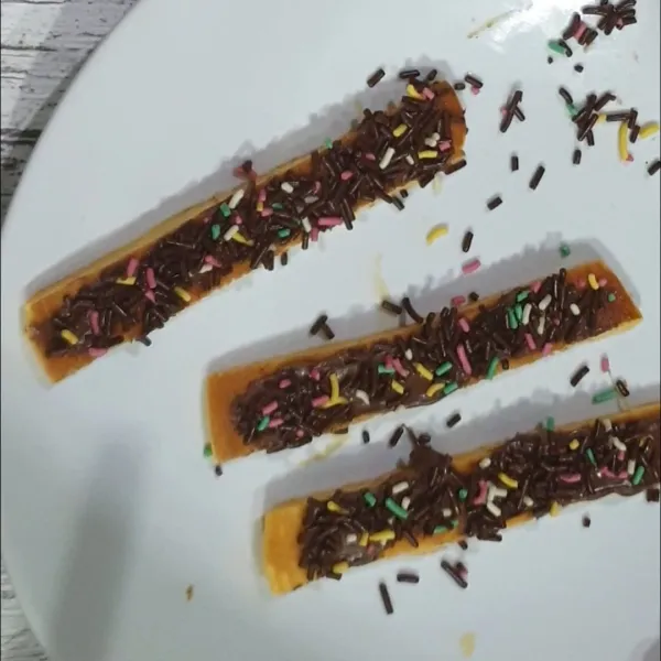 4. Ambil 1 buah pancake potong memanjang sebanyak 3 pcs, oles dengan selai coklat dan ditabur coklat meses warna warni