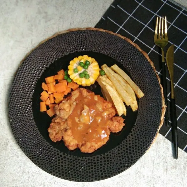 Siapkan piring saji, tata crispy chicken steak beserta kentang goreng dan sayuran rebus, siram ayam dengan sausnya, sajikan