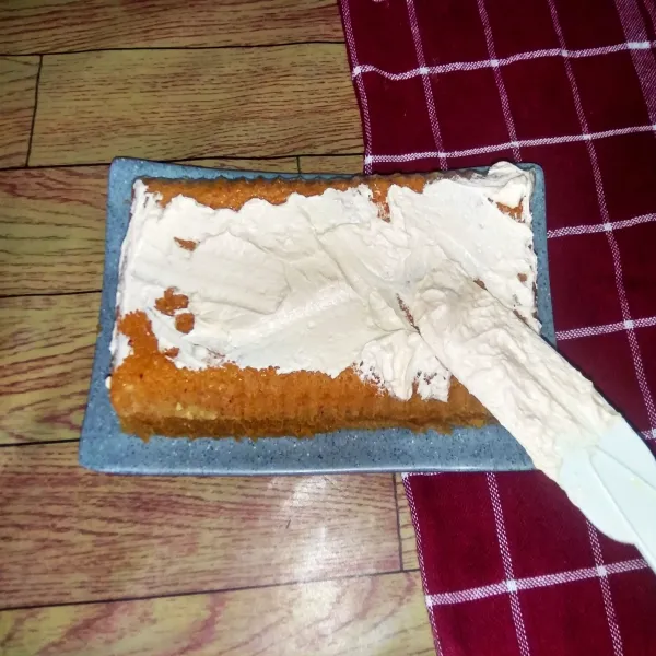 Setelah matang, dinginkan dan keluarkan kue dari loyang panggang. Olesi dengan butter cream hingga menutupi kue bolu