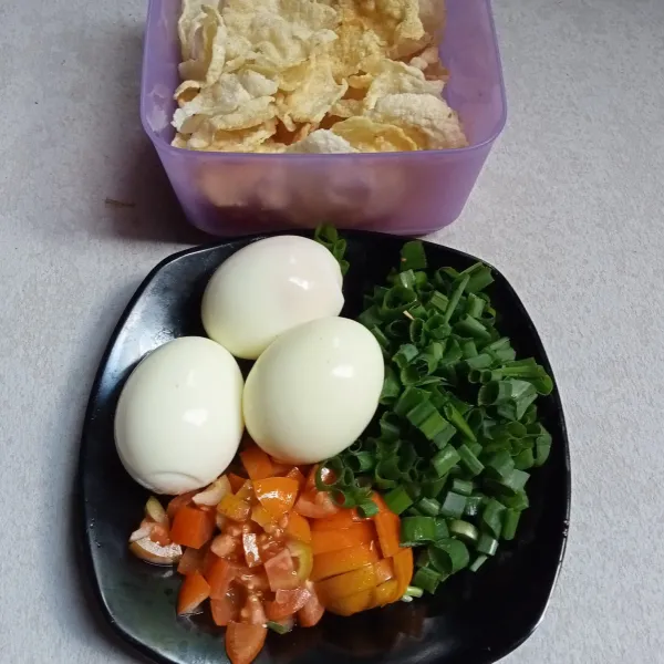 Rebus telur dan kupas kulitnya, potong-potong tomat dan daun bawang, goreng emping melinjo.