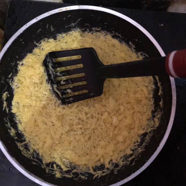 Angkat cangkir kuning telur dan tuang ke dalam minyak panas lalu aduk terus.