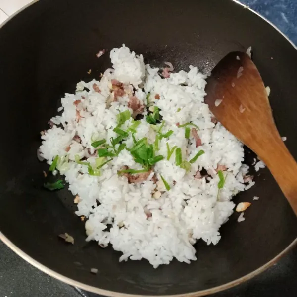 Kemudian masukkan nasi dan bawang prei. Aduk rata.