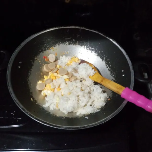 Masukkan nasi, orak-arik telur dan baso, aduk hingga merata.