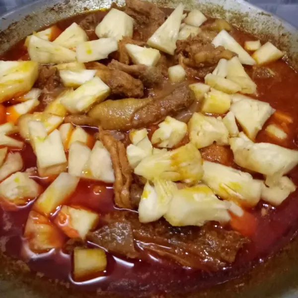 Setelah kuah mulai berkurang dan ayam sudah masak, masukkan nanas yang telah dipotong.