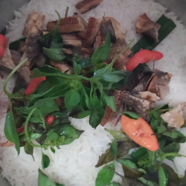 Setelah nasi pindah ke warm, masukkan cabai rawit merah, suiran ikan asin, daun kemangi dan perasan air jeruk nipis. Aduk hingga rata kemudian tekan cook kembali biarkan hingga nasi matang.