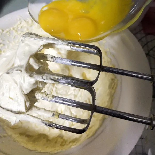 Setelah adonan menjadi pucat masukkan tiga kuning telur satu persatu dan di mixer kembali lakukan hal yang sama sampai telurnya habis