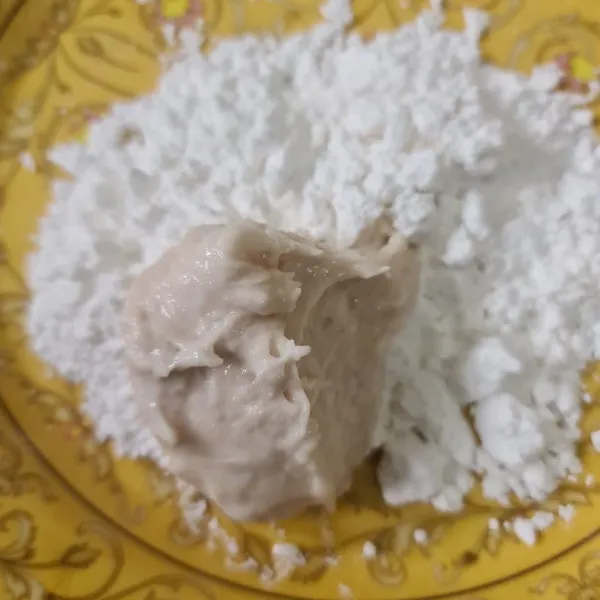 Diatas piring beri tepung sagu. Letakkan 1 sdm adonan ikan tenggiri lalu bulatkan pada tepung sagu.