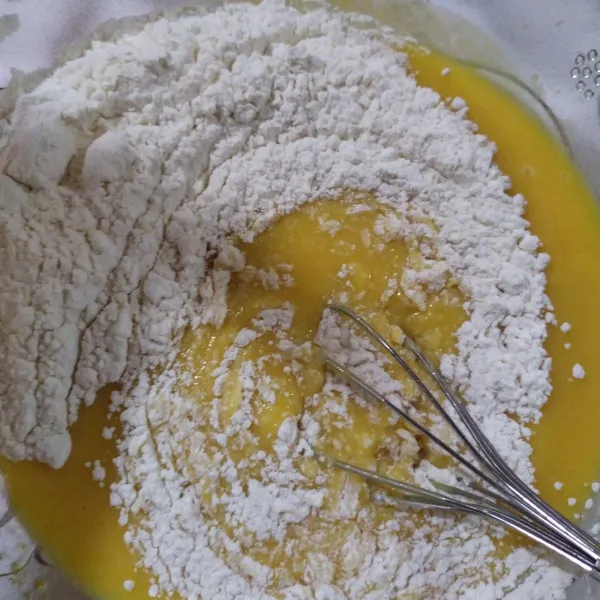 Tambahkan tepung terigu sedikit demi sedikit sambil diaduk hingga tercampur rata.