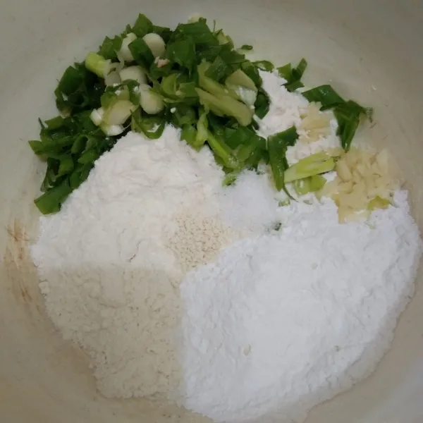 Siapkan wadah lalu campur tepung beras, tepung terigu, garam, kaldu jamur, bawang putih, dan daun bawang. Aduk rata.