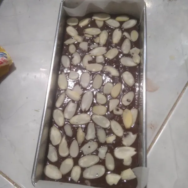 Tuang ke dalam loyang yang sudah diolesi margarin dan dialasi baking paper. Beri taburan almond slices diatasnya.