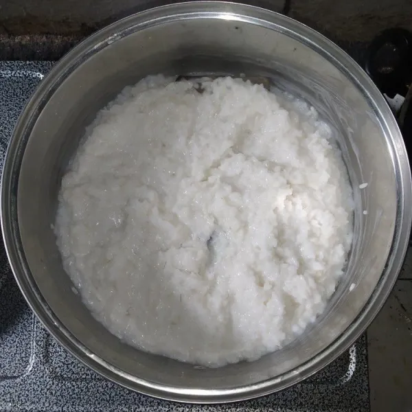 Aduk-aduk beras yang sudah setengah matang, kemudian masukkan santan, garam, dan 250 ml air, panaskan kembali dengan api kecil.