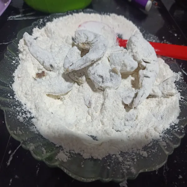 Masukkan udang yang telah dimarinasi ke dalam tepung kering dan lumuri sampai semua bagian tertutup tepung