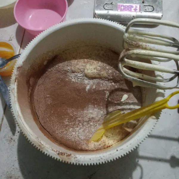 Masukkan pasta coklat, lalu masukkan tepung terigu, tepung maizena, coklat bubuk dan baking powder yang sudah diayak. Aduk rata dengan spatula.