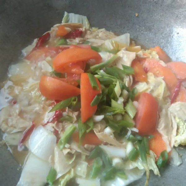 Tambahkan irisan tomat dan bawang daun, masak hingga matang