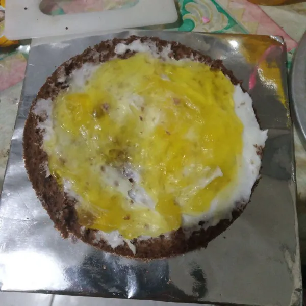 Potong cake menjadi 2 bagian, oles dengan buttercream dan selai nanas lalu tumpuk dengan bagian lain.