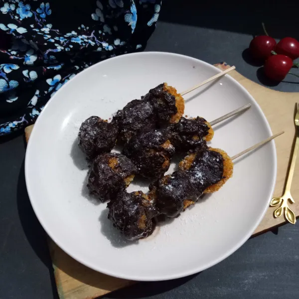 Celup sate pisang dalam cokelat cair, taburi sedikit gula halus, sajikan.