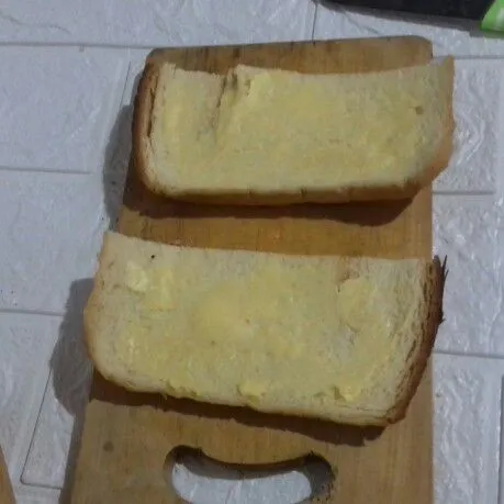 Potong roti jadi 2 bagian. Pipihkan dengan roling pin dan oles dengan margarin.