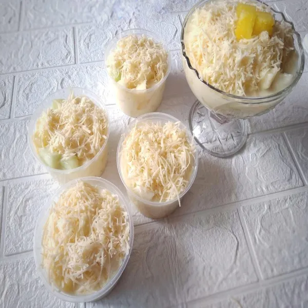 Taruh salad buah di mangkuk kecil. Dan salad buah siap disajikan dengan parutan keju di atasnya.