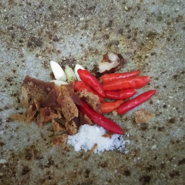 Dalam cobek, haluskan cabe rawit, bawang putih, kencur, garam, dan gula merah.