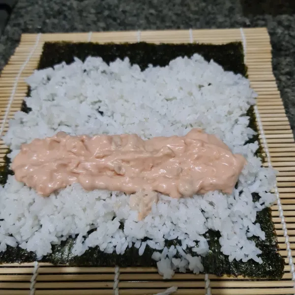 Bentangkan nori di atas sushi mat. Beri nasi dan tambahkan salmon mayo.