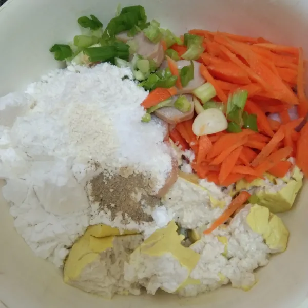 Dalam wadah campur tahu, wortel, sosis, bawang daun, bawang putih, bawang merah, garam, kaldu jamur, merica bubuk, tepung terigu dan tepung tapioka, aduk rata