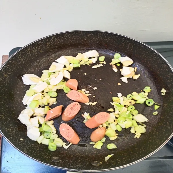 Tumis batang daun bawang dan bawang putih hingga layu, masukkan sosis dan telur asin lalu aduk rata.